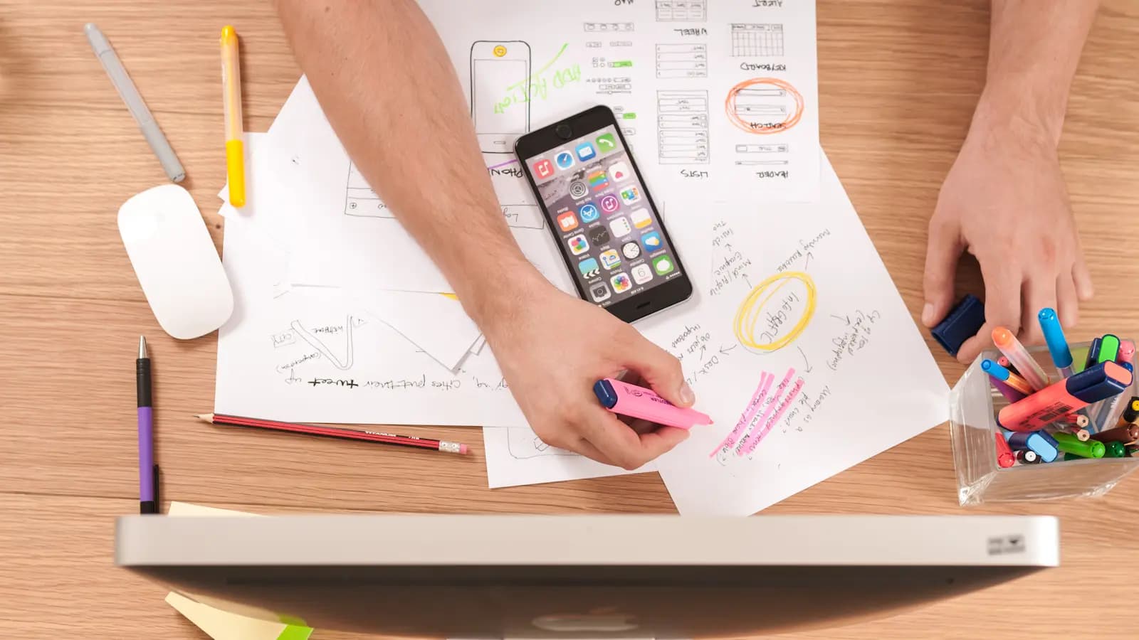 Hand sketching website wireframes beside a phone